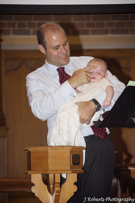 Sign of cross on baby boy being christened - christening photography sydney